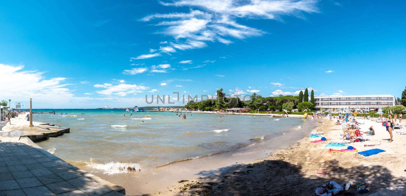 Luxury sand beach in Borik, Zadar Croatia, people sunbathing and swimming, luxury hotels in background righ next to the beach. District of Puntamika