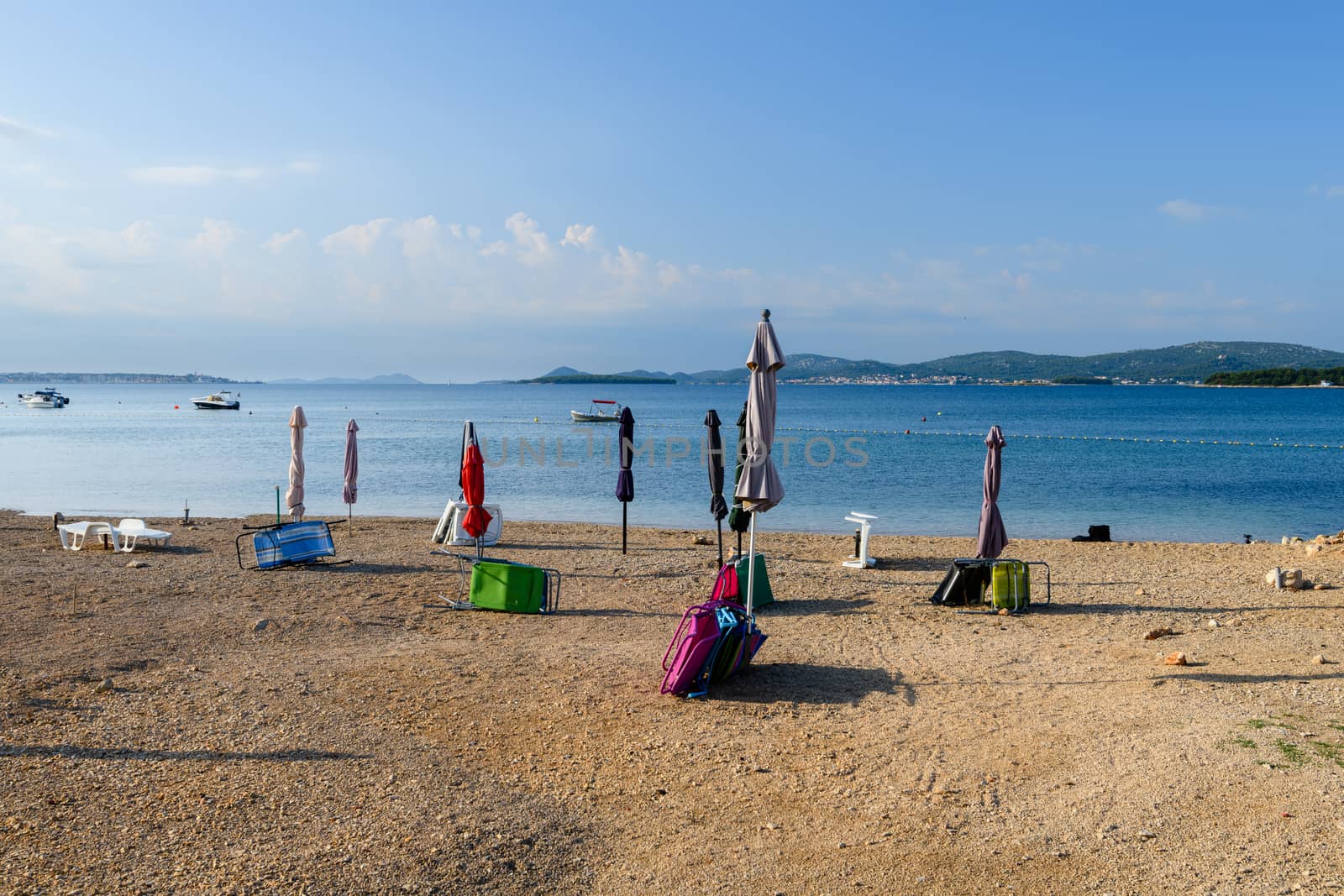 Beach in Turanj, small village in Dalmatia, Croatia, island of Pasman in background, sunchairs, parasols, umbrellas and beach requisites