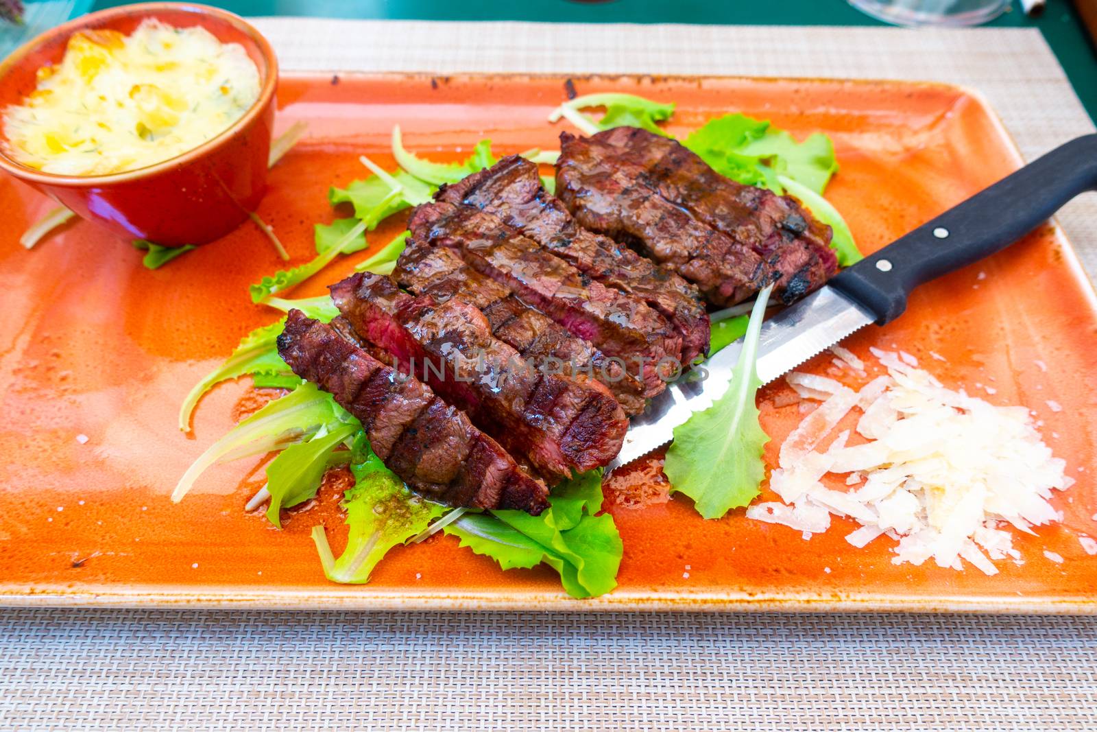 Traditional Italian Tagliata Steak with Parmesan and Salad as close-up on a plate by asafaric
