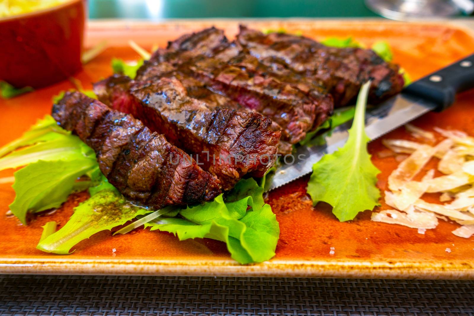 Traditional Italian Tagliata Steak with Parmesan and Salad as close-up on a plate by asafaric