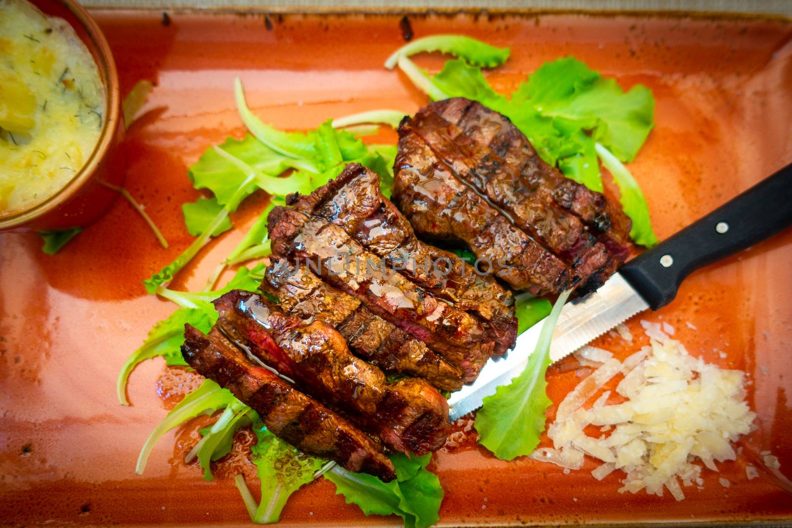 Top view of Traditional Italian Tagliata Steak with Parmesan and Salad as close-up on a plate