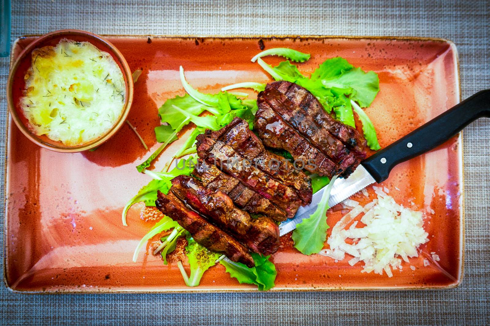 Top view of Traditional Italian Tagliata Steak with Parmesan and Salad as close-up on a plate, salad sparkled with Aceto Balsamico vinegar