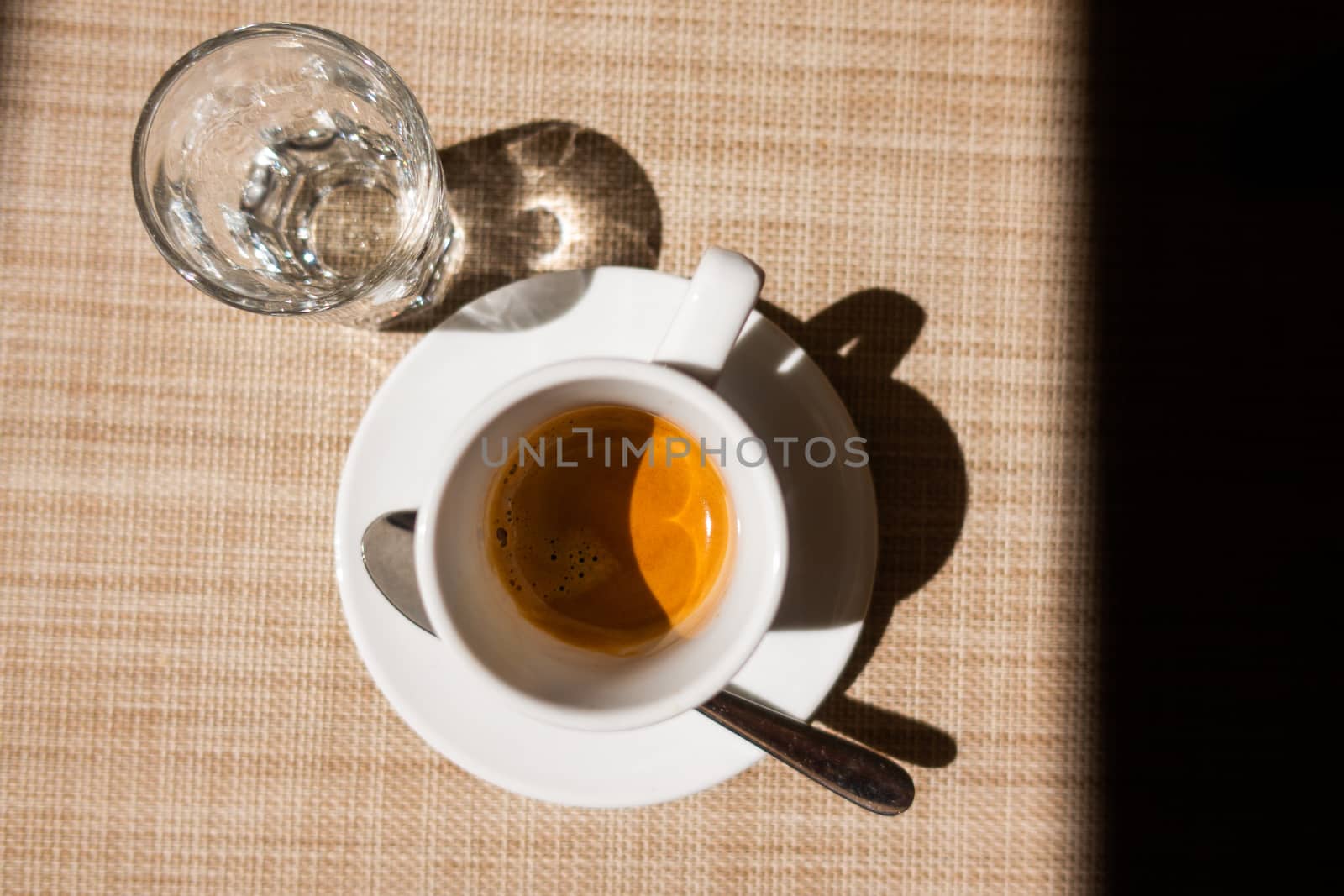 Caffe corretto, traditional Italian beverage with espresso and a shot of liquor, usually grappa, top view on beige background and dark frame to right, copyspace