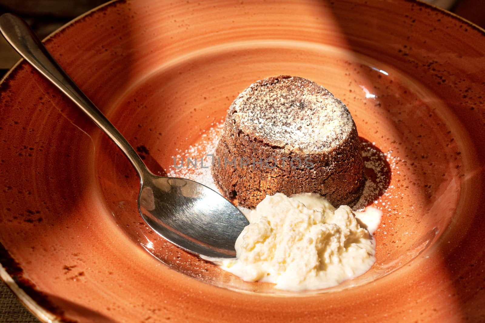 chocolate souffle on brown plate with whipped cream, close up shot, framed with light and shadow