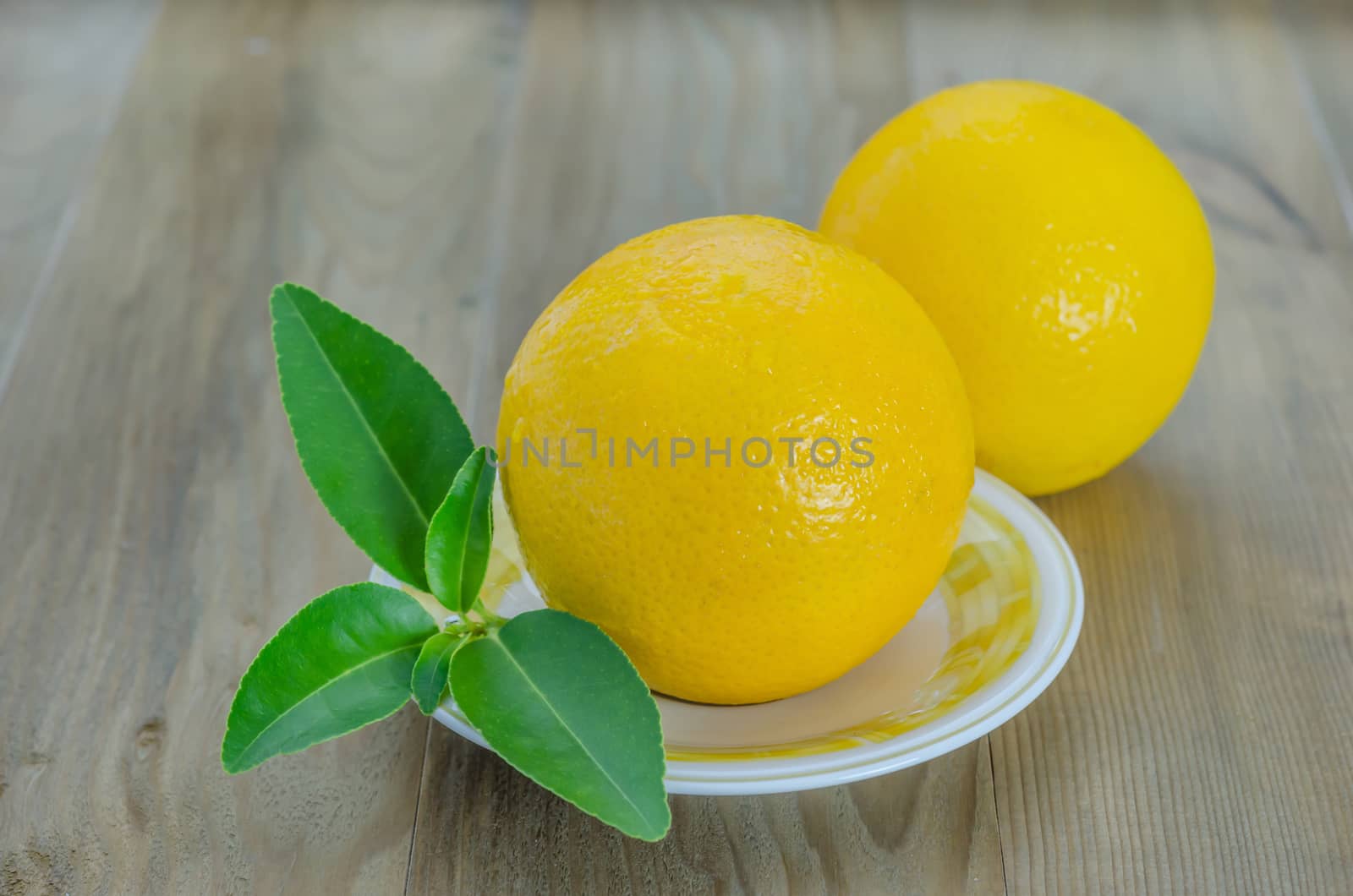 ripe orange with leaves on dish over wooden background