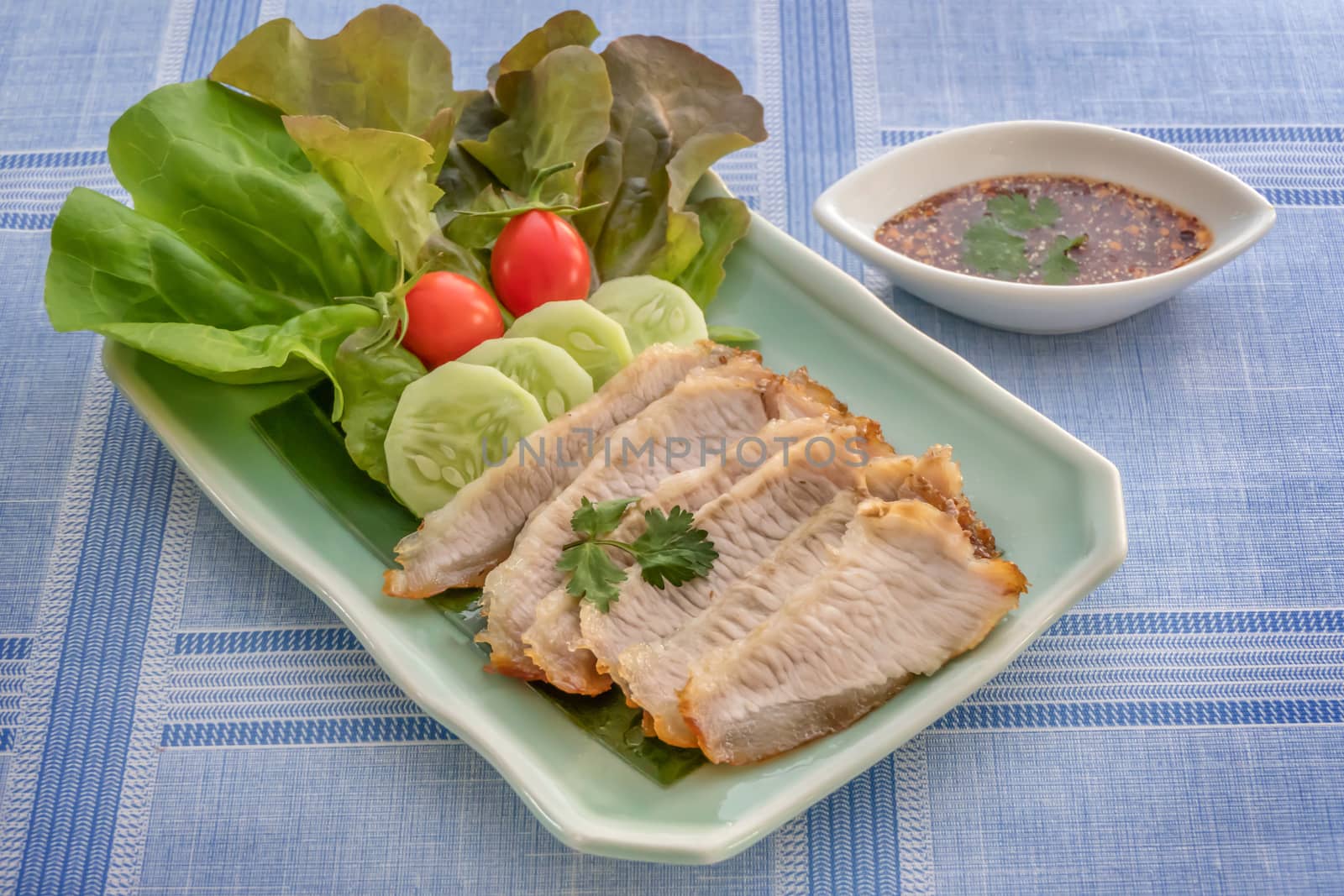 slice of grilled pork served with fresh vegetable and spicy sauce , Thai style food