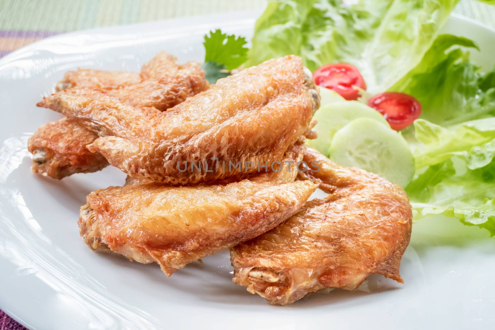 Fried chicken wings served with fresh vegetable on plate