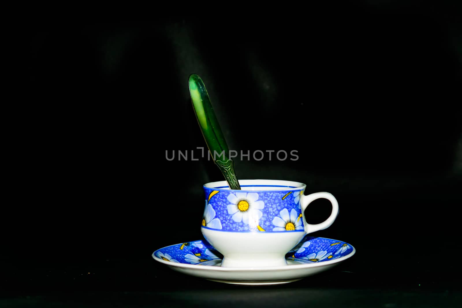 Single coffee cup on the plate with spoon in dark background