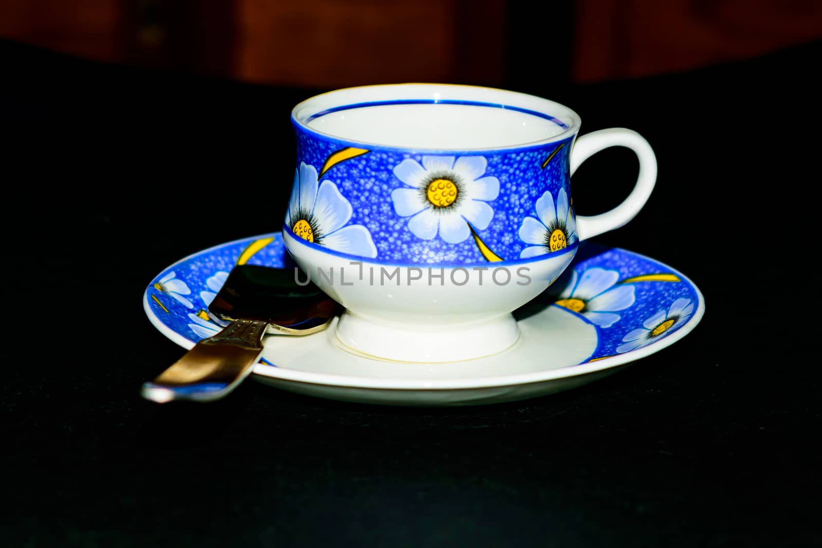 Single coffee cup on the plate with spoon in dark background