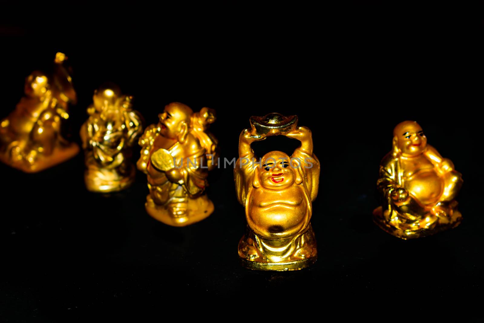 A Golden Laughing Buddhas with relaxed mindset. Isolated in a dark background. Selective focus and shallow depth of field