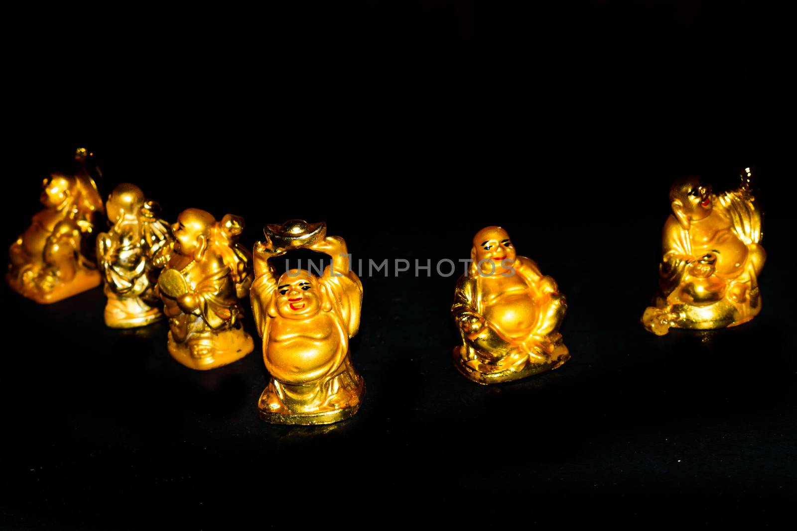 A Golden Laughing Buddhas with relaxed mindset. Isolated in a dark background. Selective focus and shallow depth of field