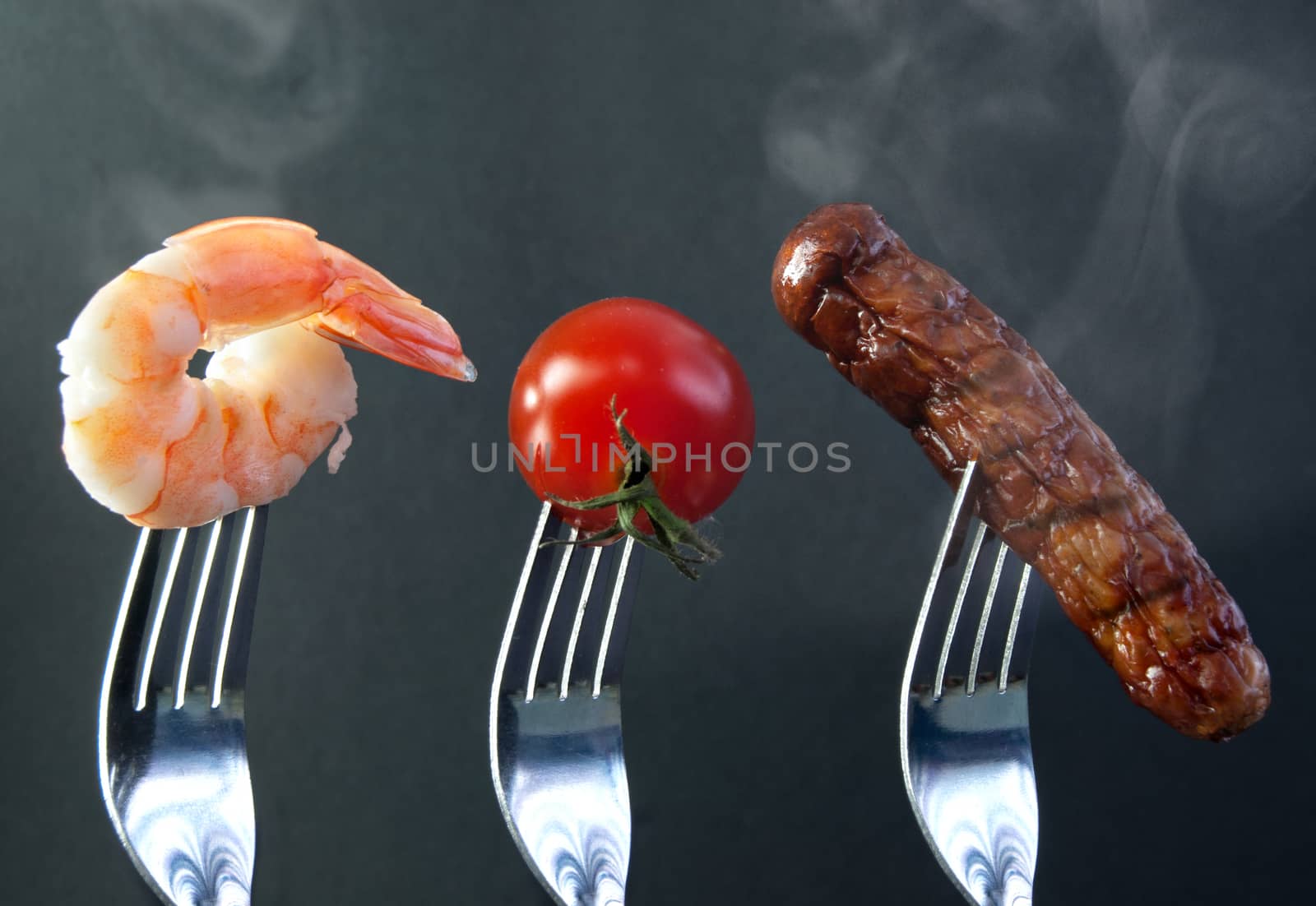 Barbecue ingredients including shrimp, tomato and sausage on forks