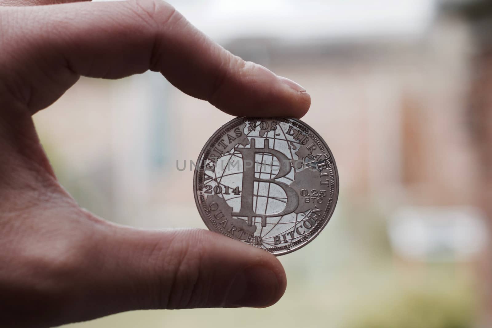 Cryptocurrency physical silver bitcoin coin holding in man fingers.