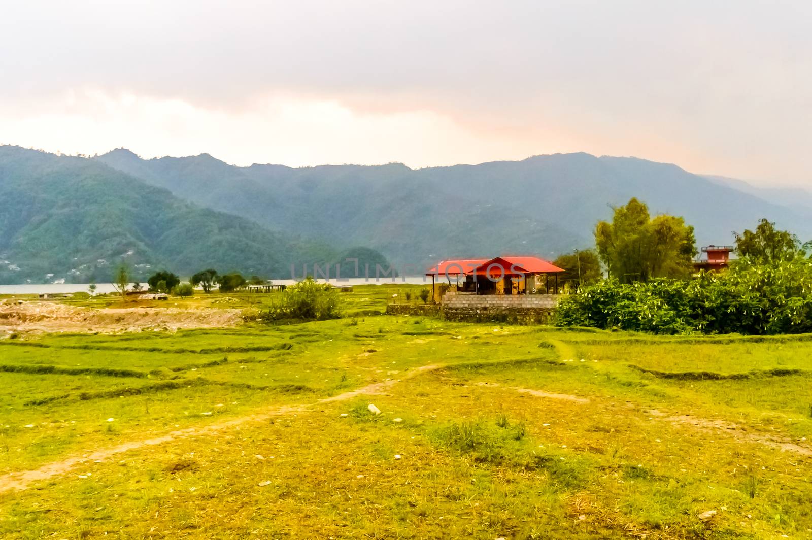 Photograph of winter season: A farm house, lake, mountain, clear sky and farm land. Wide angle landscape of Pokhara Lake at Kathmandu Nepal. Vintage film look. Vacation Freedom, Simplicity Concept. by sudiptabhowmick