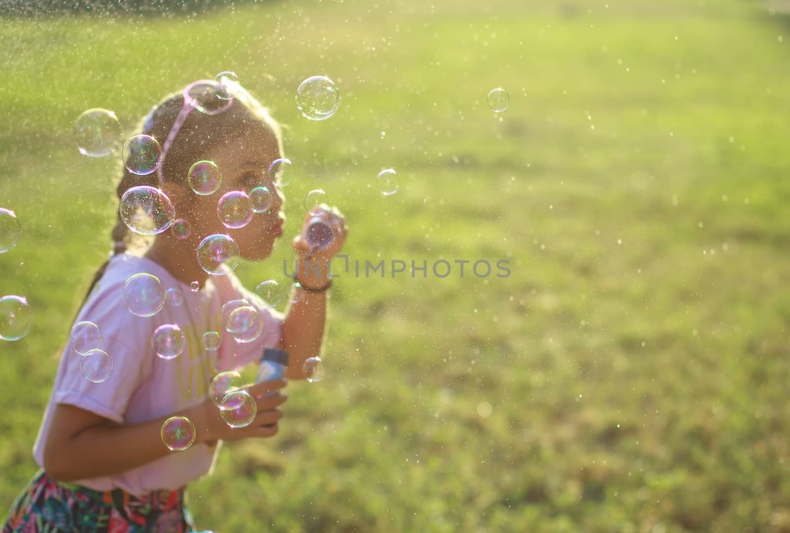 Cute girl blowing soap bubbles, bubbles in focus