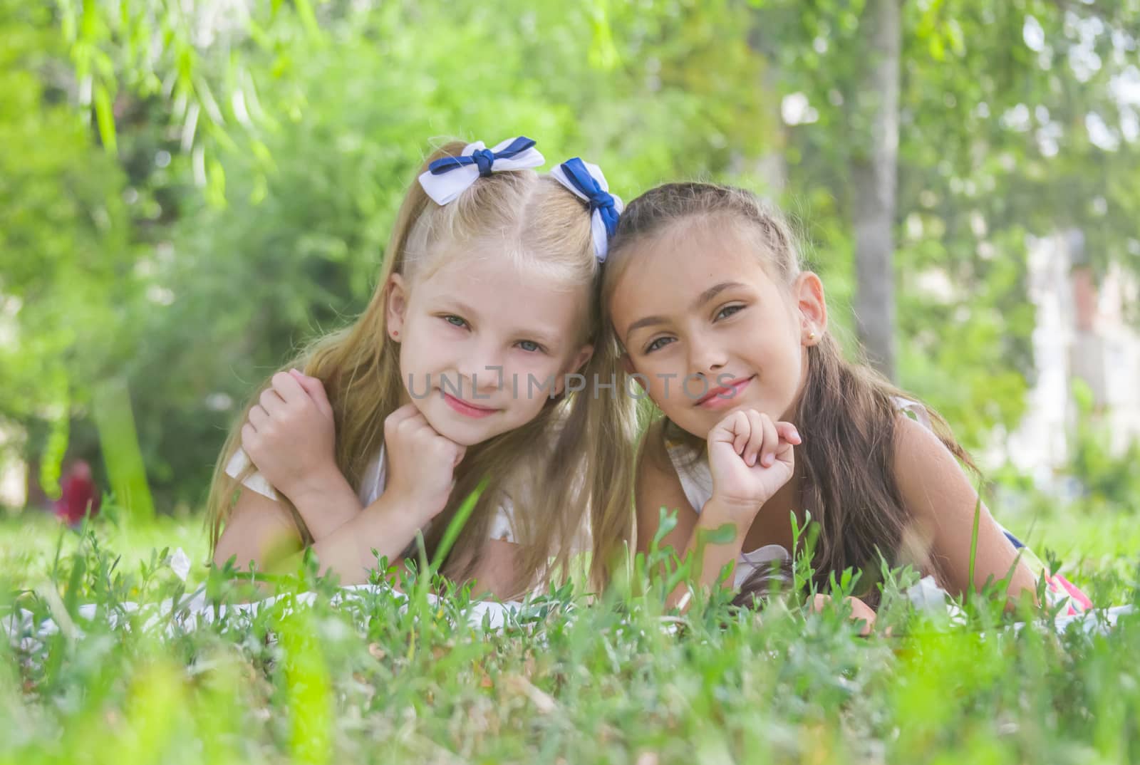 Smiling girls lying on green  grass in the park in summer by Angel_a