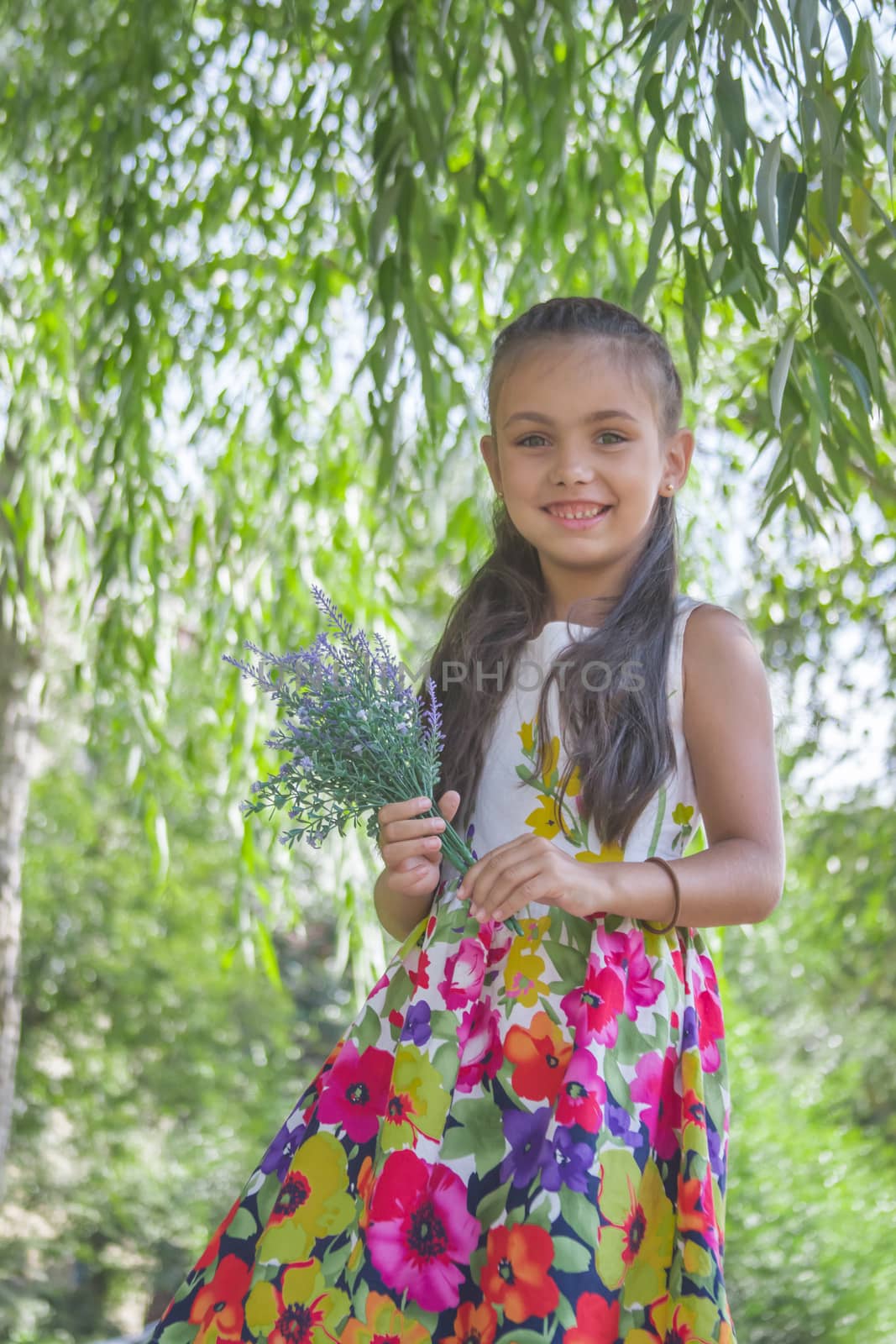 Happy cute little girl holding bouquet of lavender in park 