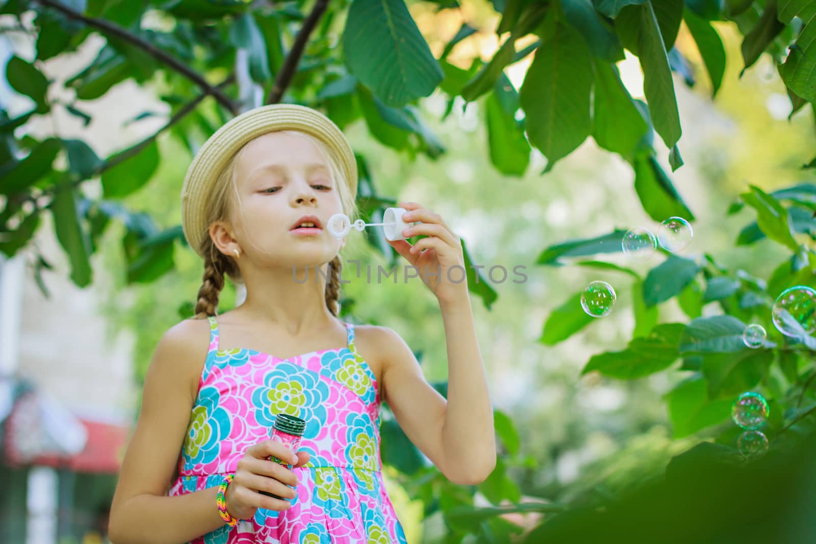 Cute girl in hat blowing soap bubbles in summer by Angel_a