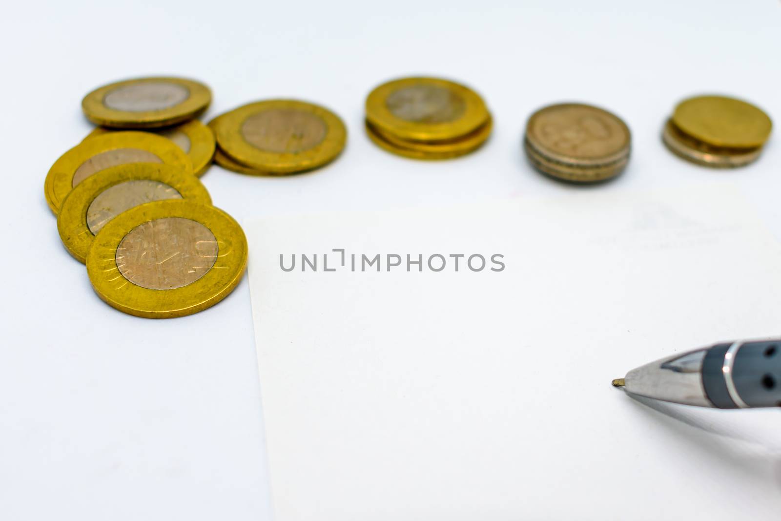 financial planning with coins and a pen isolated on a white background. Selected focus, narrow depth of field. Calculation of financial growth and investment concept