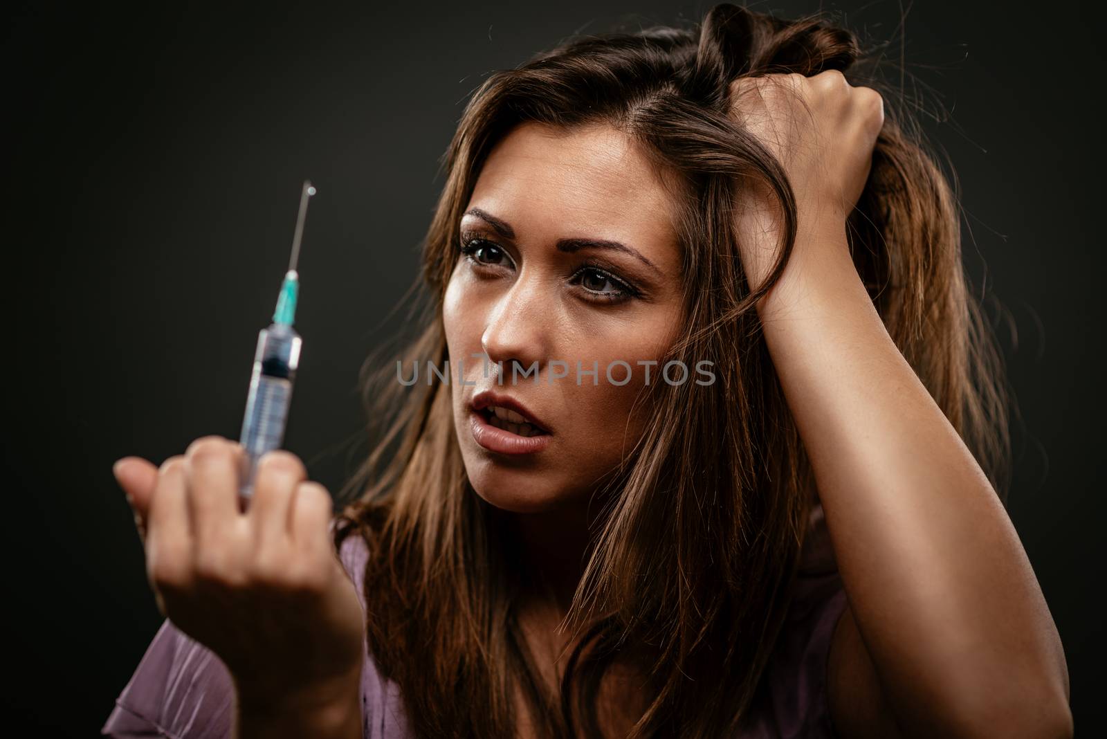 Portrait of a beautiful girl drug addiction. She is holding syringe with drugs.
