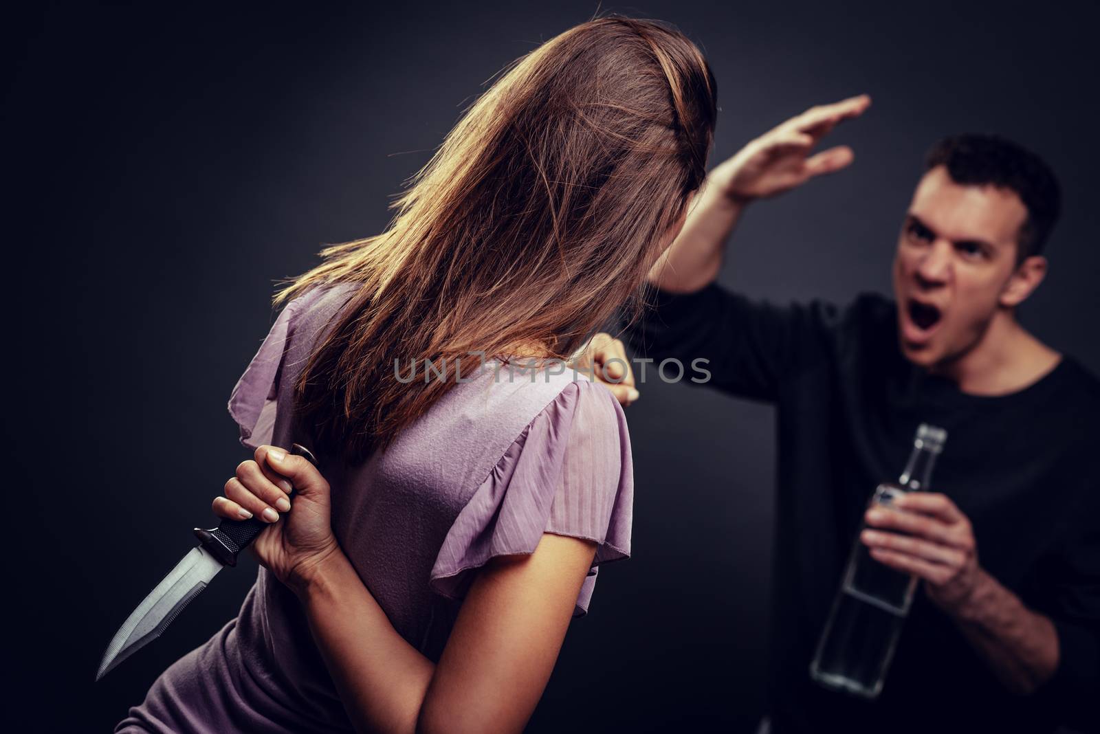 Angry aggressive drunk husband is physically abusing his wife. Selective focus.