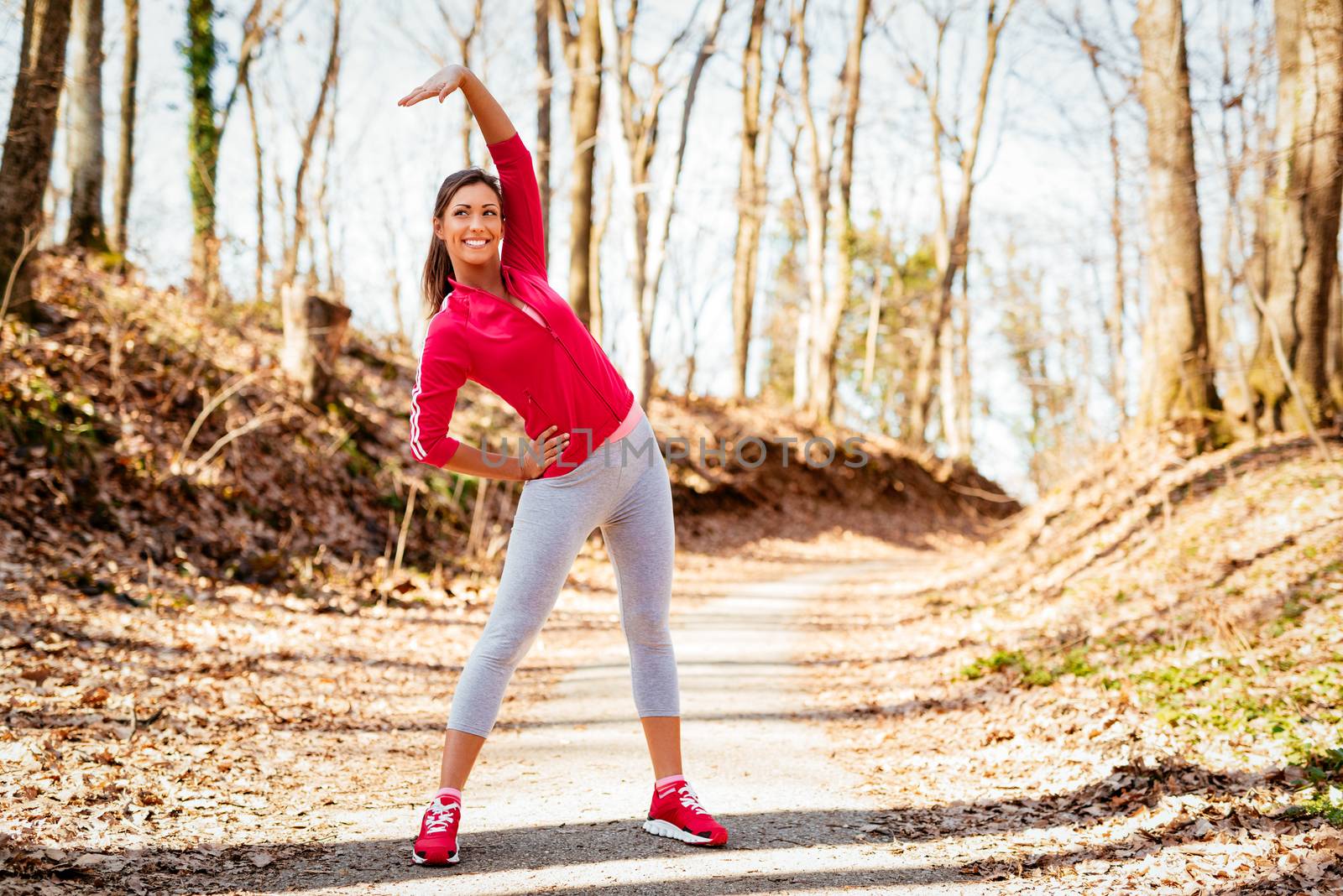 Beautiful fitness running woman doing stretching exercise in the forest. 