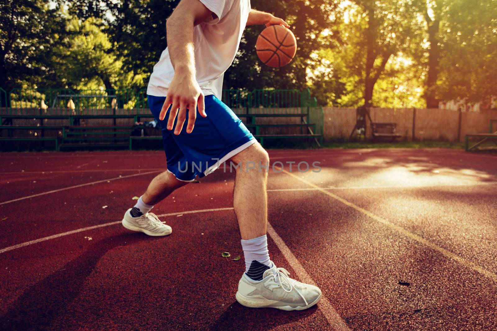 Unrecognizable young street basketball player showing his skills on court. 