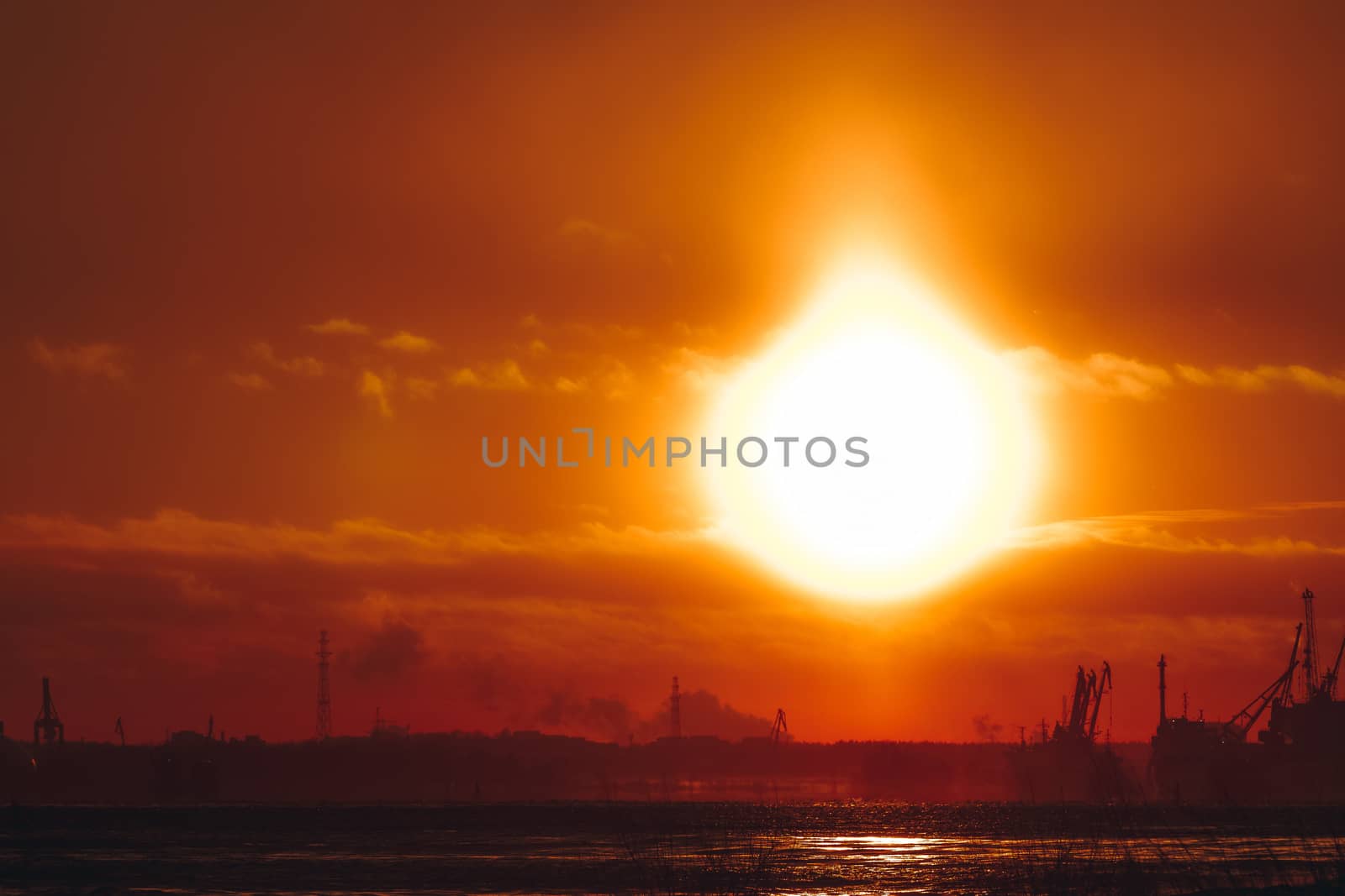Hot orange winter sunrise against the cargo port