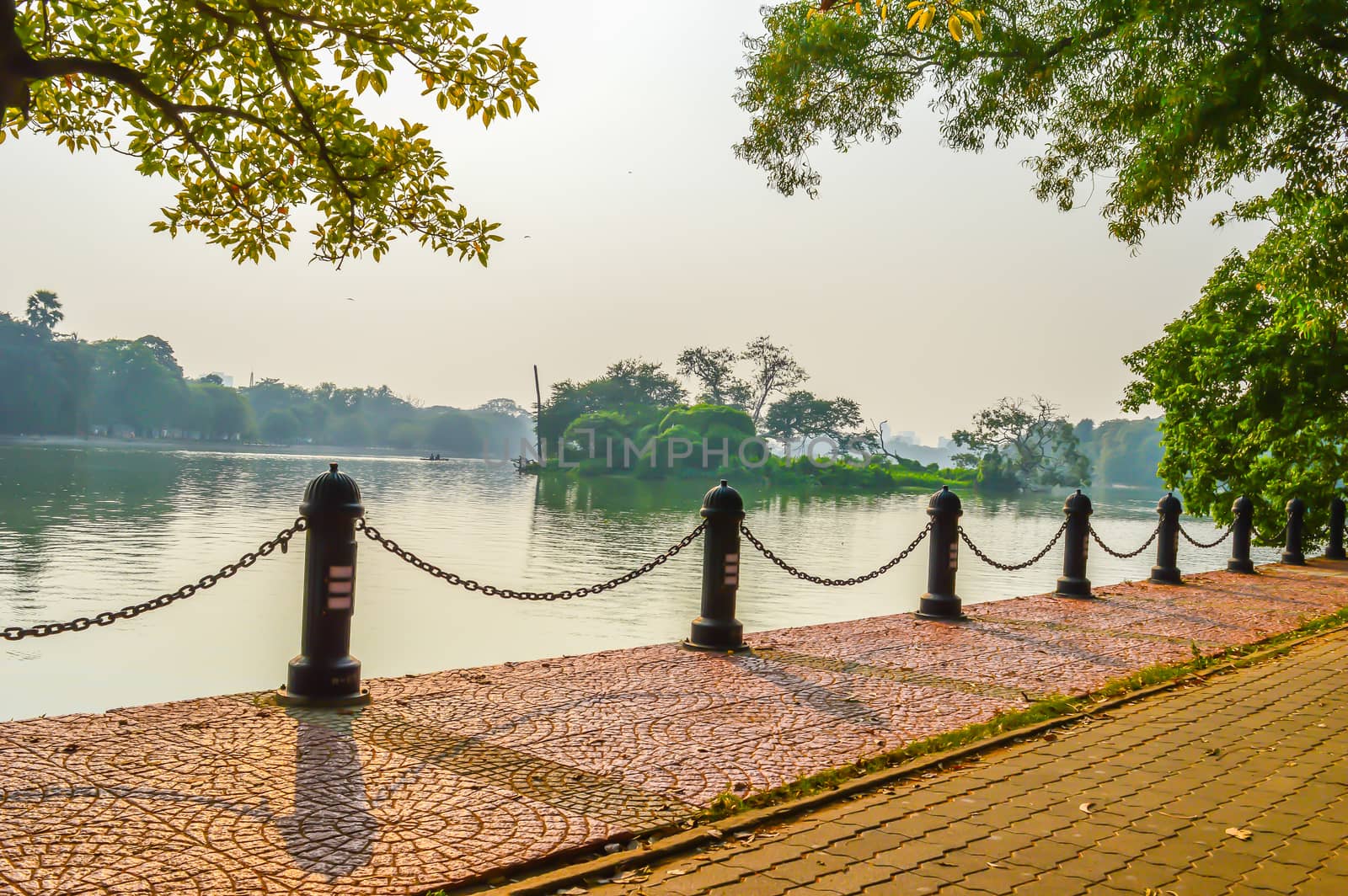 Beautiful green park & blue clear sky landscape. A line of fence and red brick path on a summer's day. The Subject of the image is adventure, inspiration, exciting, hopeful, bright, sensational, tranquil, calm, stormy, stunning. This photography is taken in as landscape style. This photograph may be used as a background, wallpaper, screen saver.