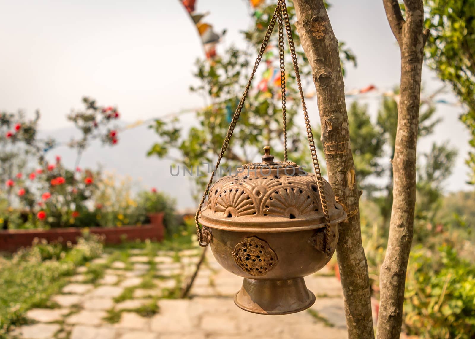 Metal Dhoop Batti Stand Hanging on a tree branch. This pot covered in a substance that is burned to produce a pleasant smell, especially as part of a religious ceremony.