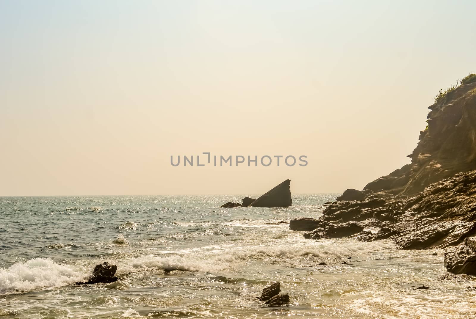 View of Beautiful sea shore at sunrise or sunset sunset. Wild Empty Tropical beach, yellow sand, mountain view, see wave, sunlight reflections taken in landscape style may be used as a background, wallpaper, screen saver banner Travel vacation concept. The image is exciting, bright, sensational, tranquil, calm, stunning.