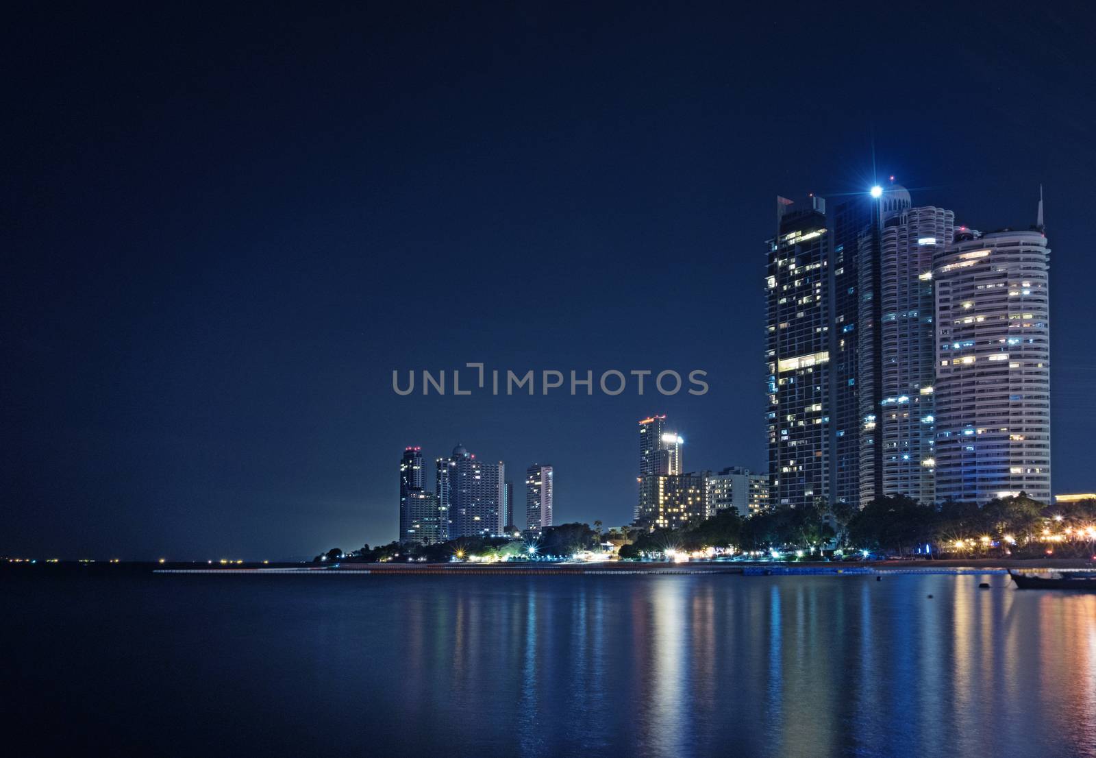 A long exposure of nigh cityscape at the beach. Light from building is reflect on the water.