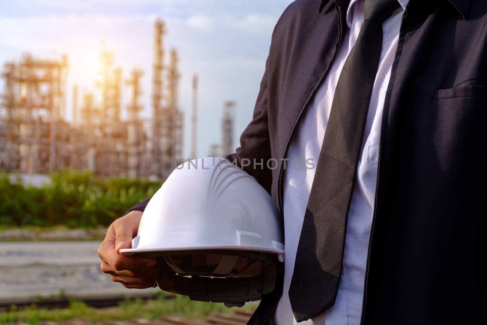 The engineer is holding a safety helmet on large industry background. The construction manager on the industry background.