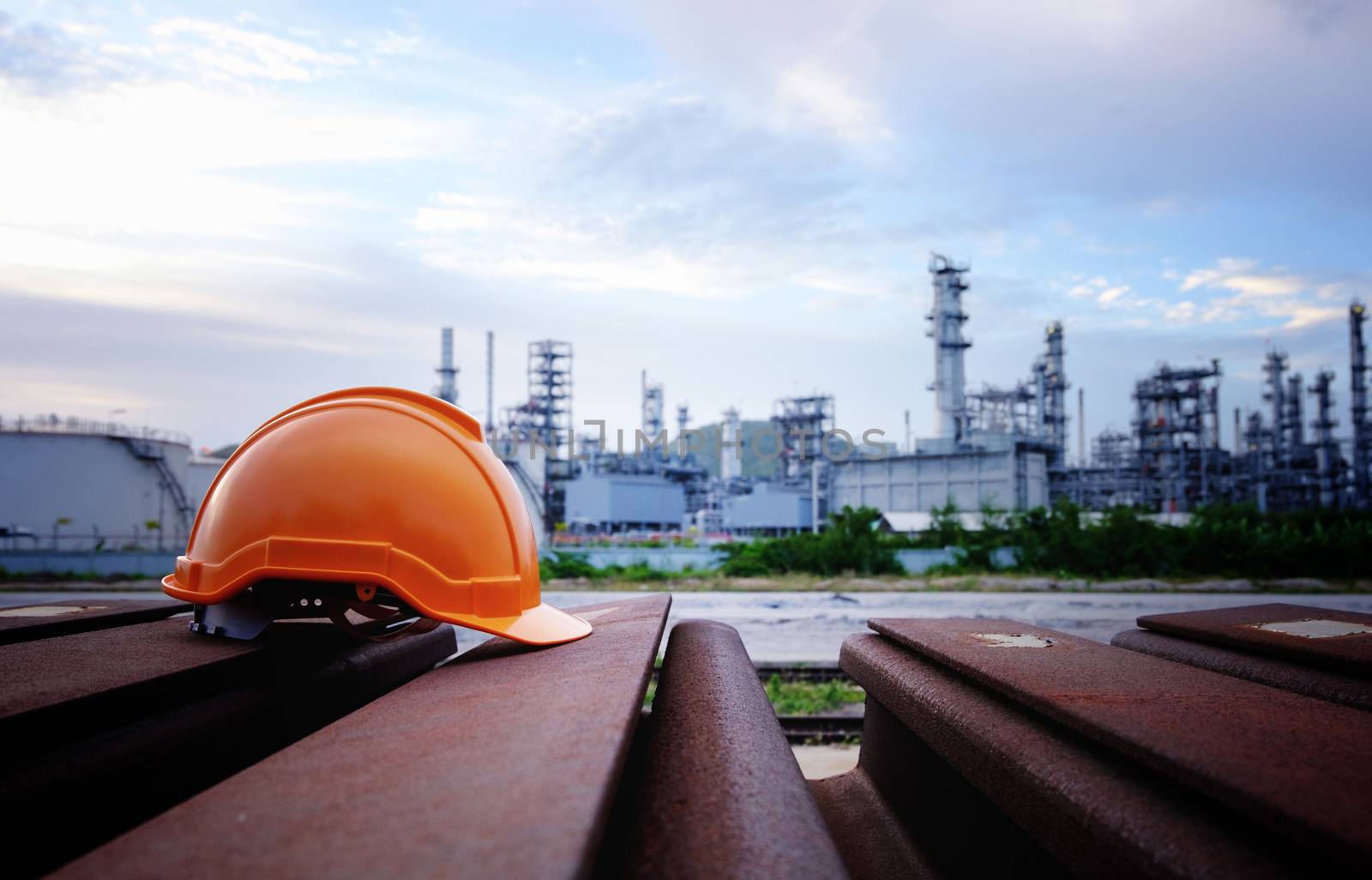 The orange salety helmet on the iron bar on the industrial background.