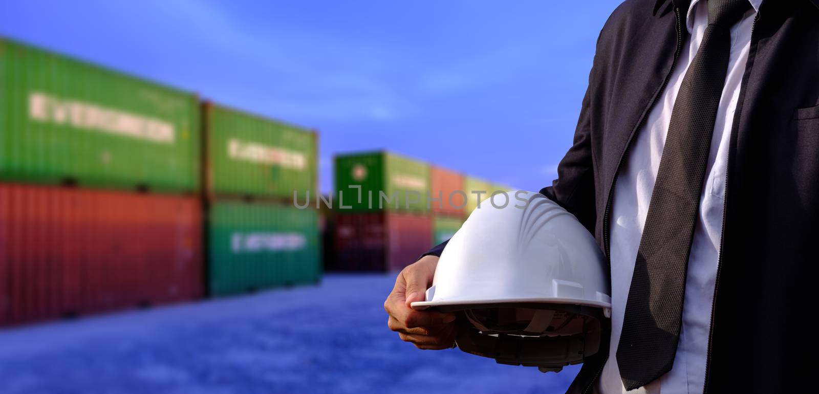 The engineer is holding a helmet on containers background. by 0864713049