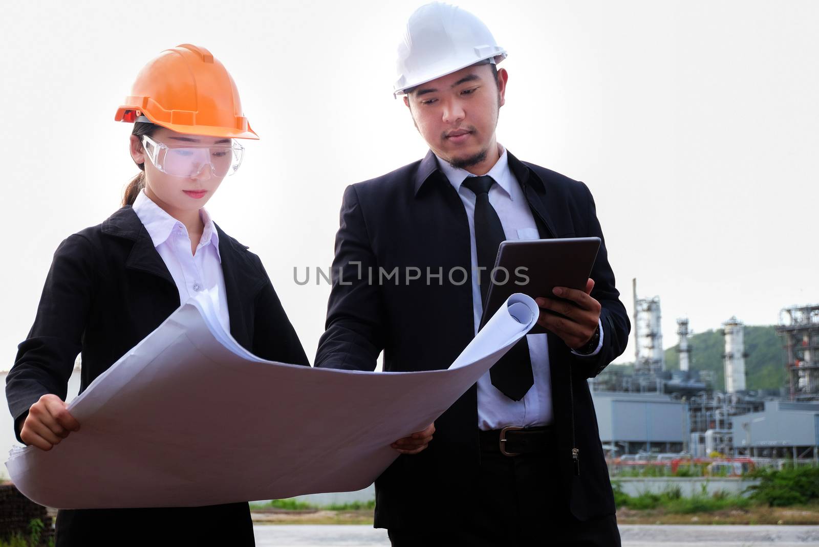 The engineer is checking a layout on large industry background. The construction manager on the industry background.