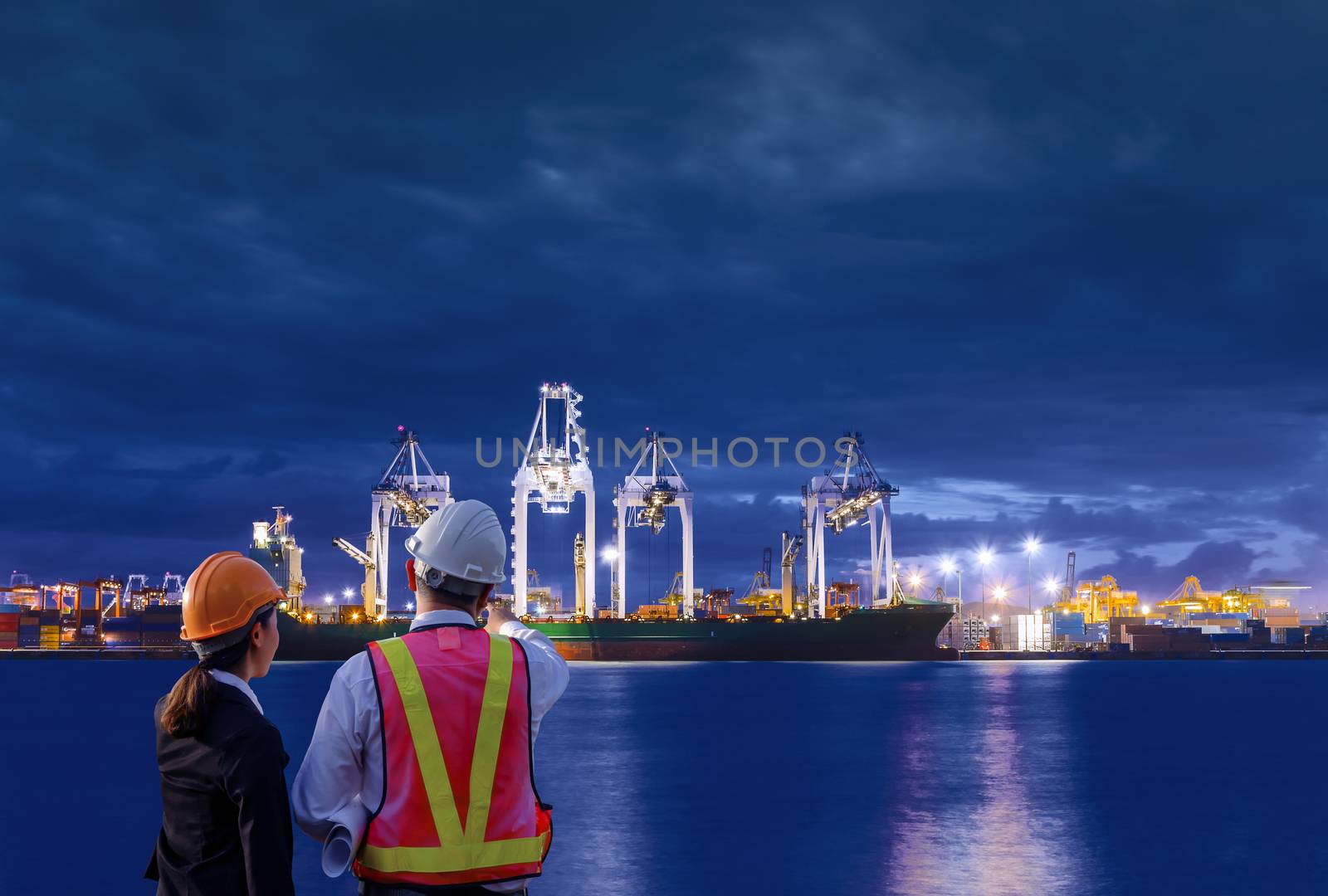 The engineers are standing on large industry background. The construction manager on the industry background.