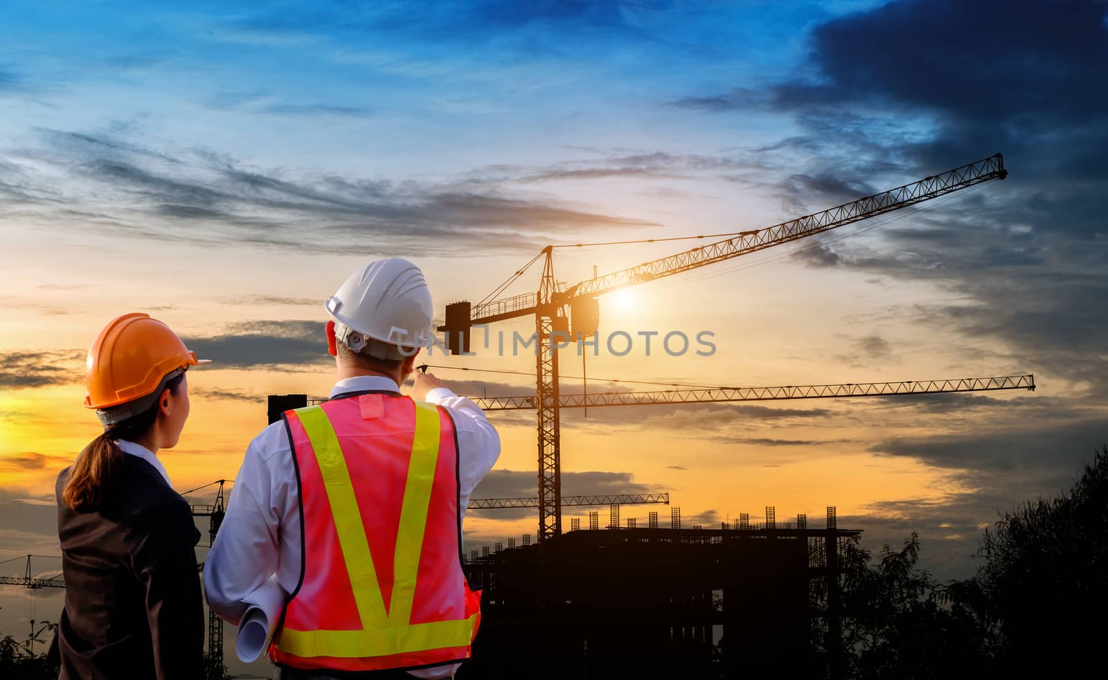 Engineers are standing survey work on construction over blurred Worker in  construction site and sunset.