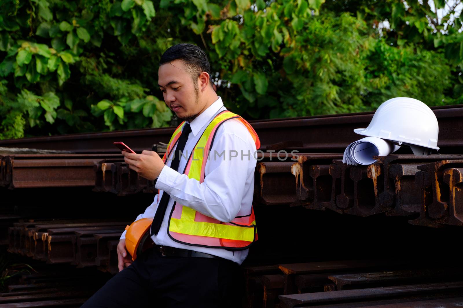 The engineer is working with smart phone on large industry background. The construction manager on the industry background.