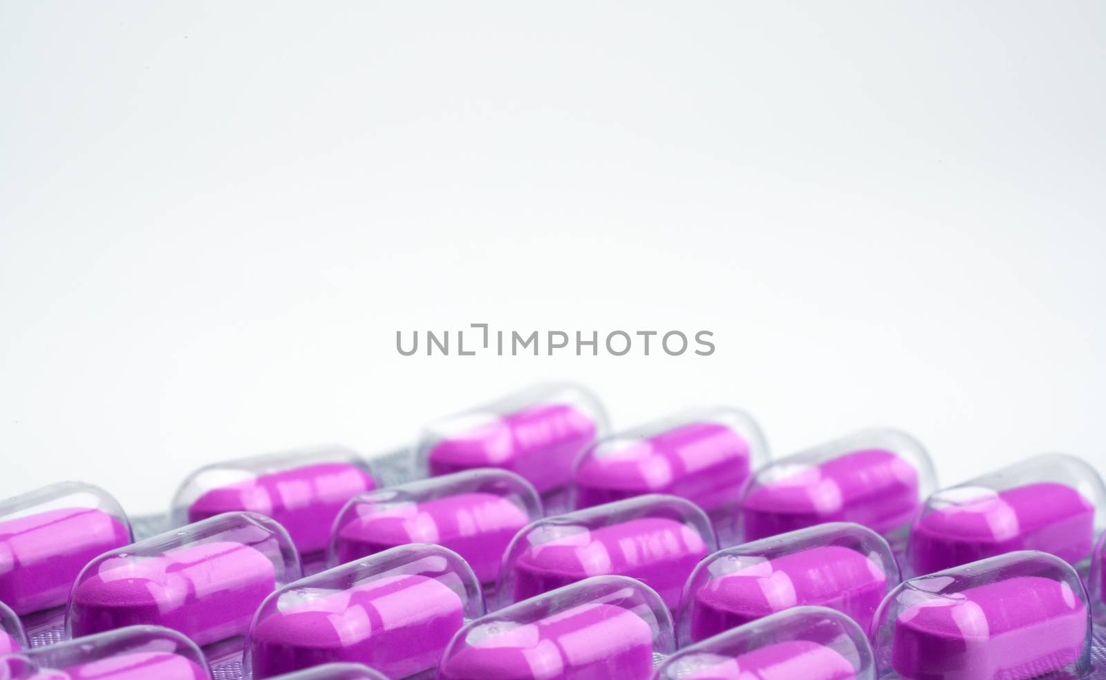 Macro shot of purple caplets pills in blister pack on white background. Mild to moderate pain management. Pain killer medicine. Pills for treatment heart broken concept. NSAIDs. Pharmaceutical packaging industry. Pharmacy background. Global healthcare concept. by Fahroni