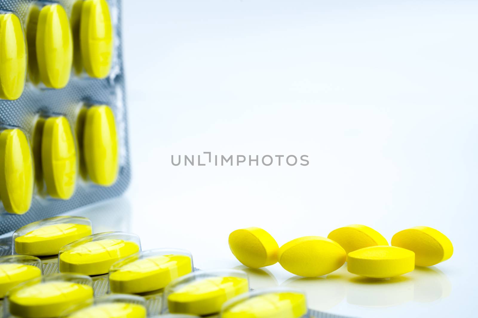 Macro shot detail of yellow oval tablet pills with blister packs on white background with copy space. Pain killer medicine. NSAIDs. Pharmaceutical packaging industry. Pharmacy background. Global healthcare concept. by Fahroni