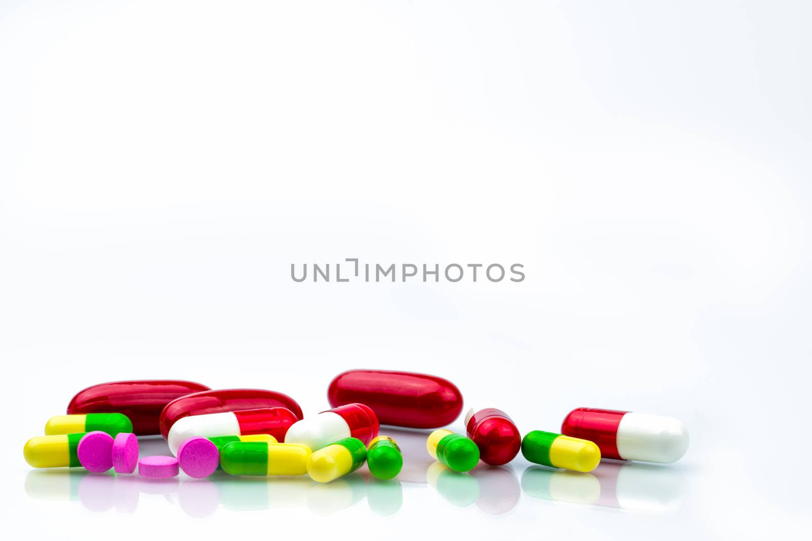 Colorful of capsule and pink tablets pills on white background with copy space for text. Global healthcare concept. Pharmaceutical industry. Pharmacy background. Pharmacology and drug interactions. Drug allergy. by Fahroni