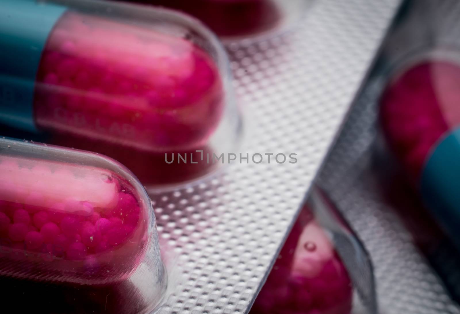 Selective focus of blue, pink capsule with granule in side pills. Pills in blister pack on white background. Pharmaceutical dosage form and packaging. Anti-fungal medicine. Pharmaceutical industry. Pharmacy background. Global healthcare concept.