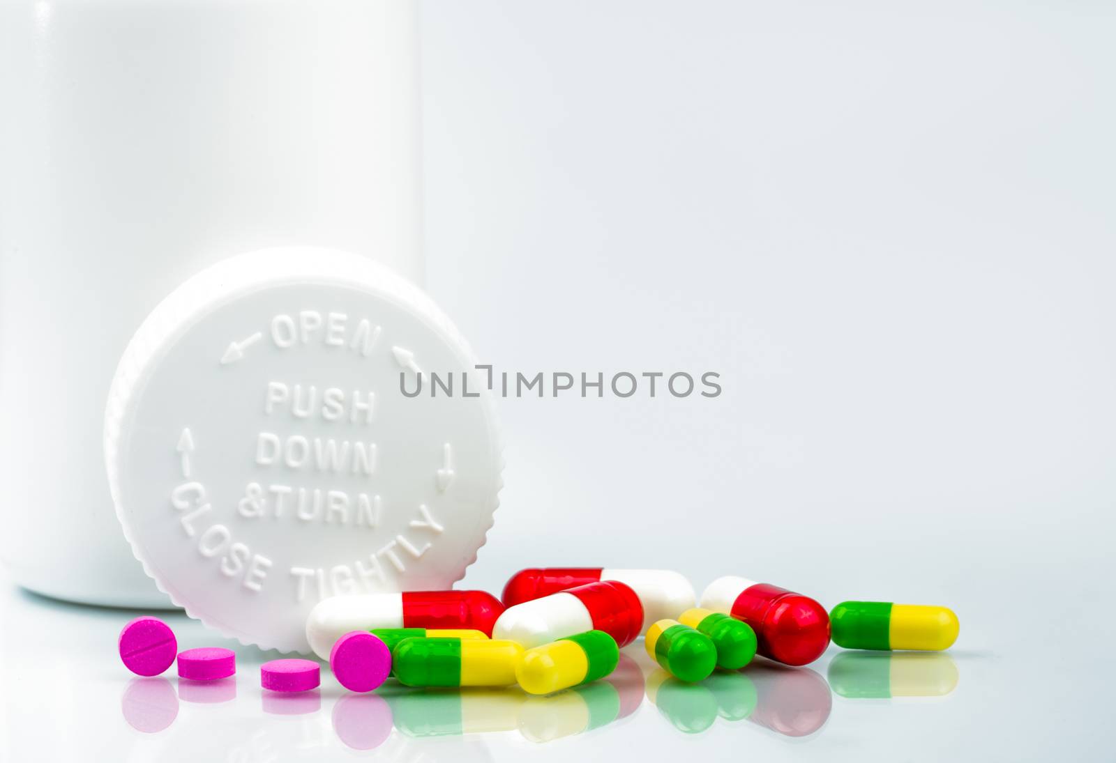 Colorful pills on white background and childproof bottle with blank label and copy space. Pharmacy department in the hospital concept. Drug store concept. Pharmaceutical industry. Pharmacy background. Pharmacology and drug interactions concept. Global healthcare.