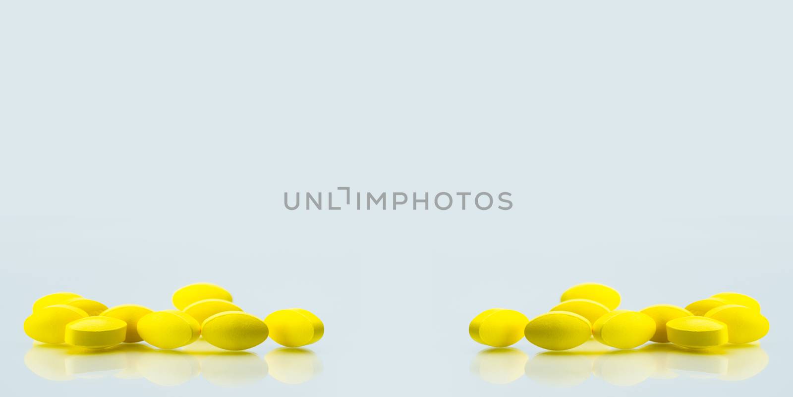 Yellow oval tablet pills with shadows on white background with copy space for text. Mild to moderate pain management. Pain killer medicine. NSAIDs drug. Pharmaceutical industry. Pharmacy background. Global healthcare concept.