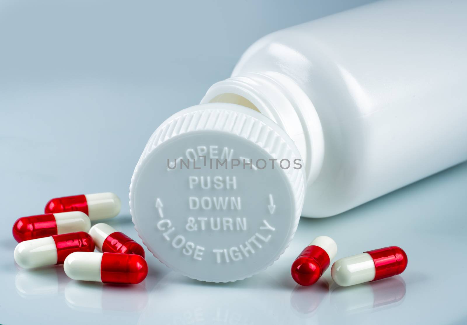 Capsules pills on white background and plastic bottle with blank label and copy space. Childproof packaging. Child resistant pill container. Push down and turn cap.Global healthcare and love concept. Pharmaceutical industry. Pharmacy background.