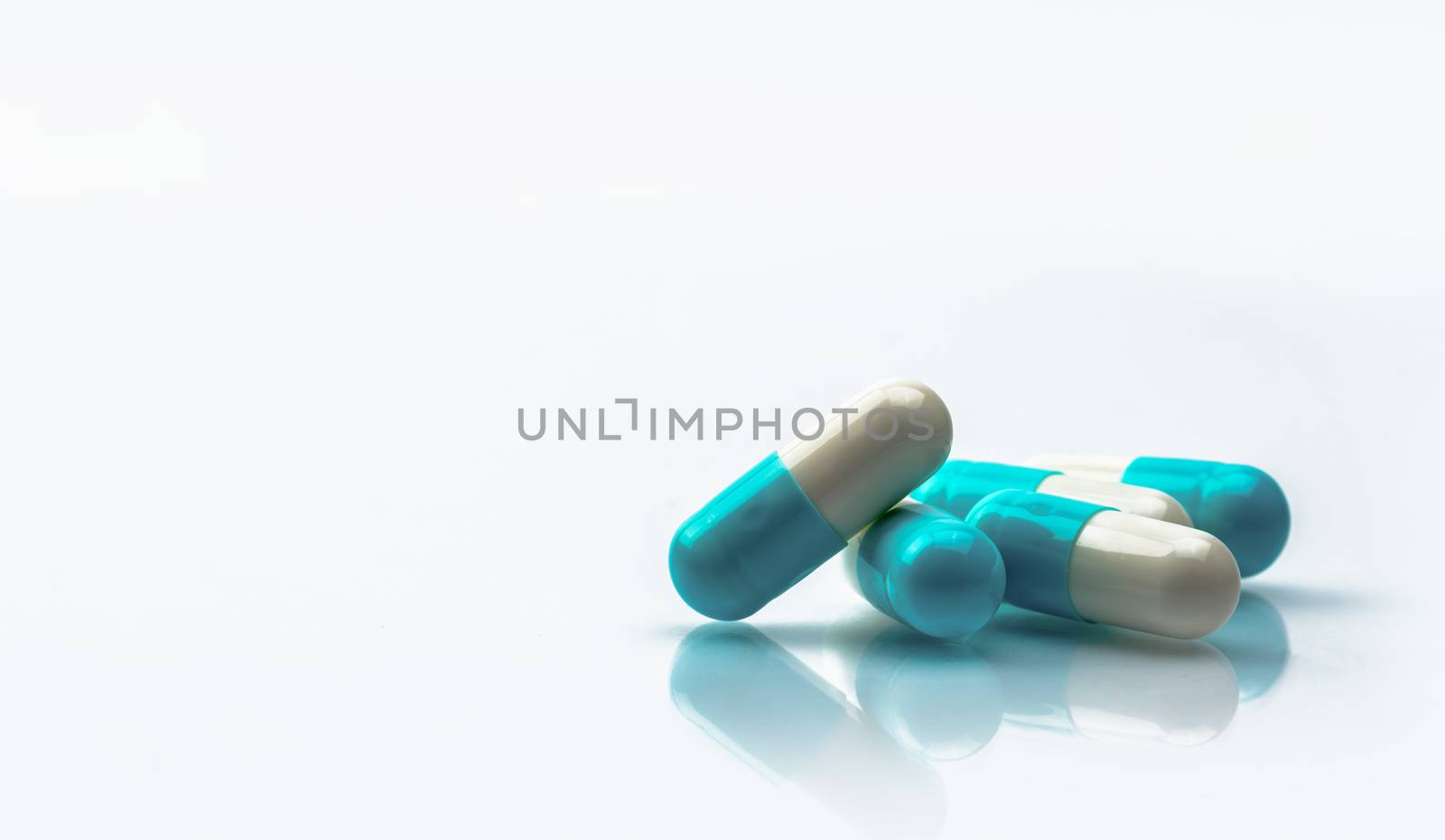 Blue and white capsules pill isolated on white background with shadow and copy space. Global healthcare concept. Antibiotics drug resistance. Antimicrobial capsule pills. Pharmaceutical industry. Health budgets and policy.