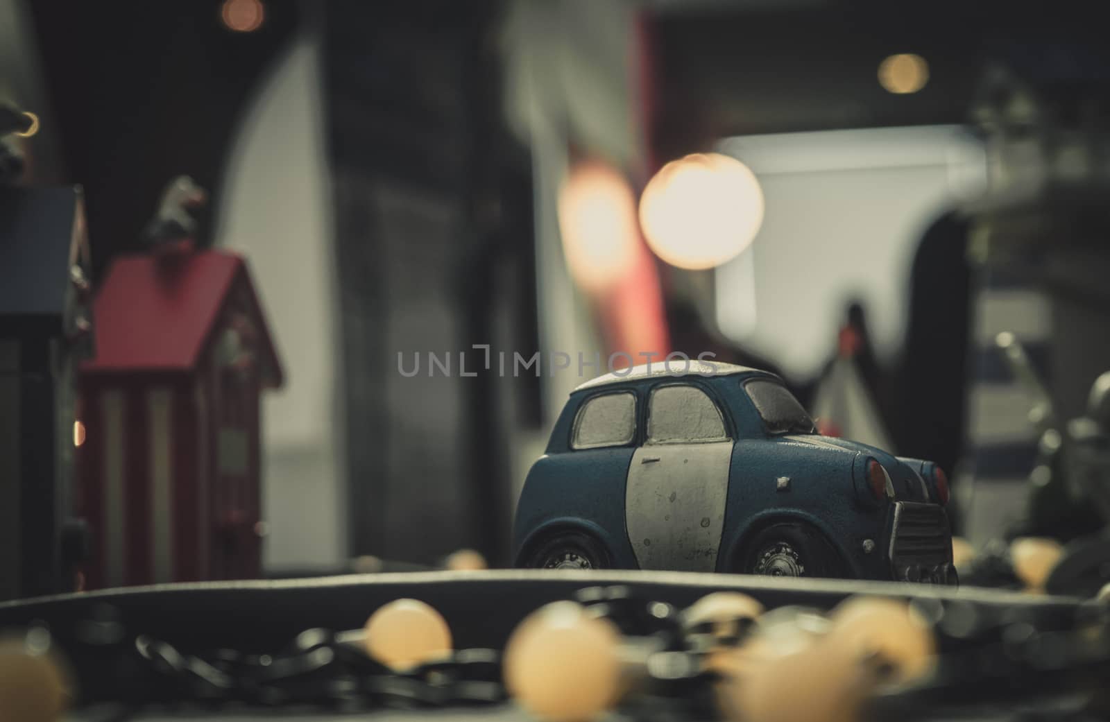 Blue and white small car toy model on the road. Mini car toy in the city near building on blurred background  with bokeh. Cartoon miniature car. World of imagination. Romantic dating night. by Fahroni