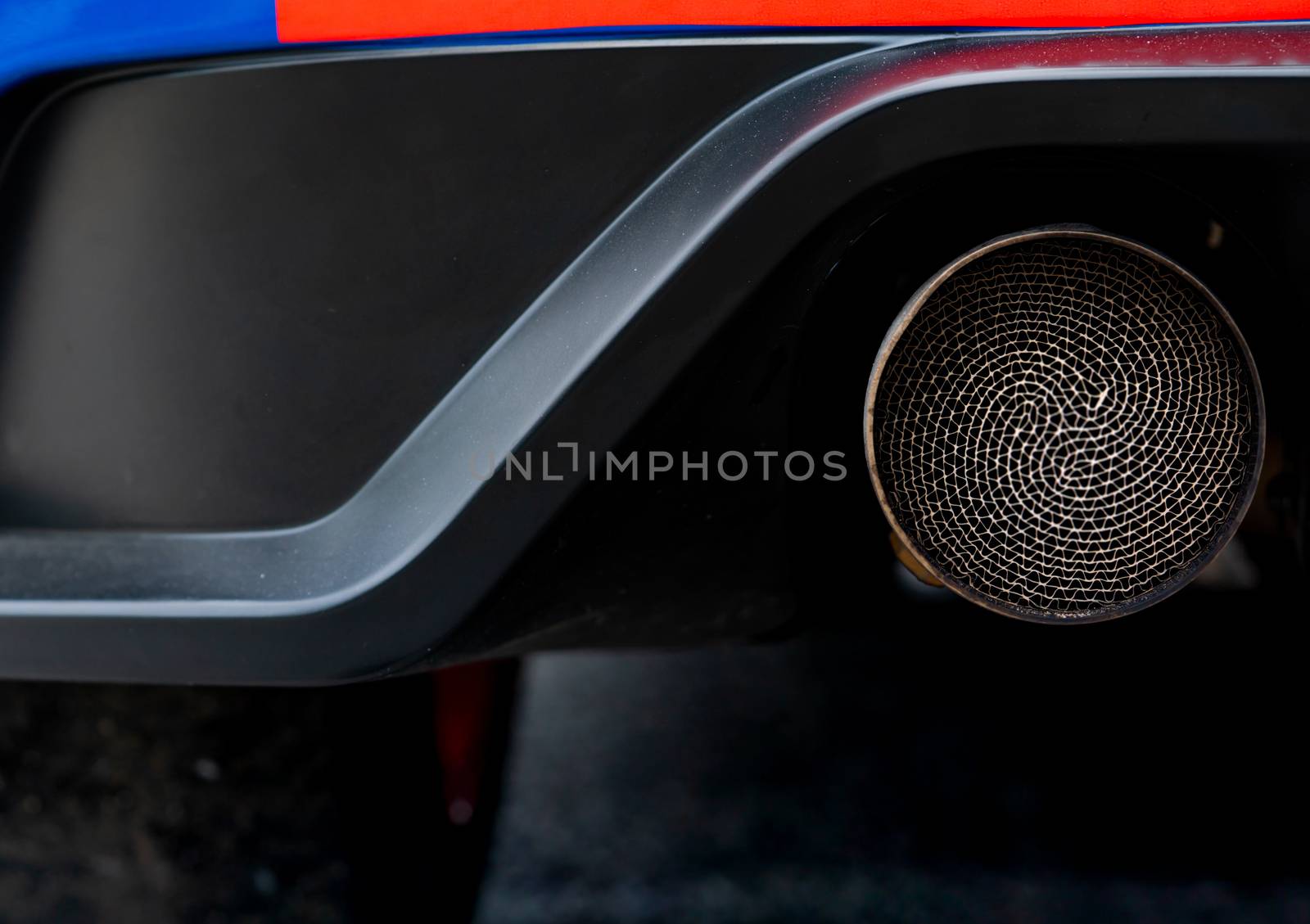 Close up detail exhaust pipe of blue SUV car. Unique pattern of car exhaust pipe. Accessories for sports car. Black soot on old exhaust pipe of gasoline engine car by Fahroni