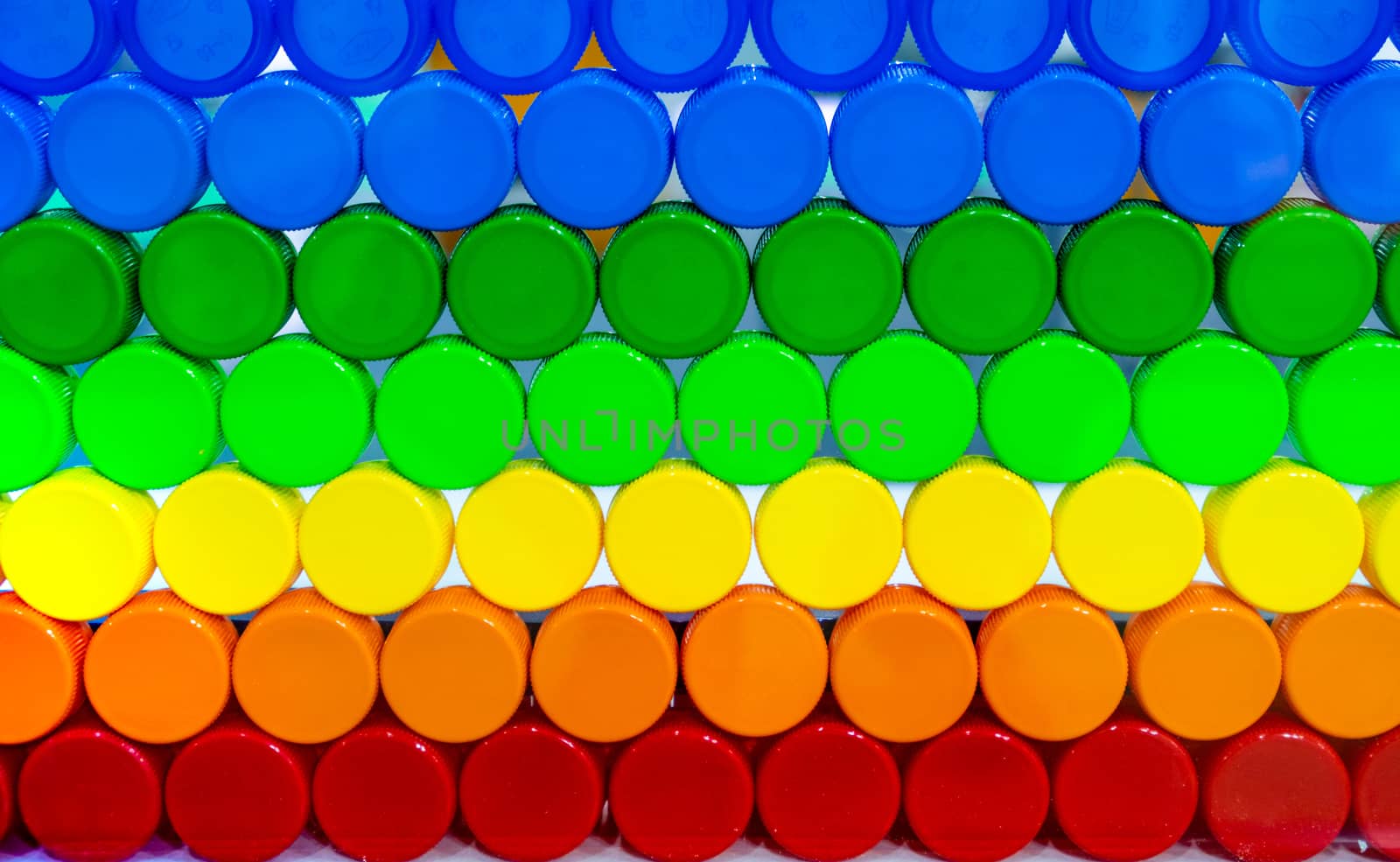 Colorful plastic bottle cap arrange with beautiful tone and pattern. Blue, green, yellow, orange, and red plastic bottle cap arrange with orderly. Cap for bottle of water, and other drink. Cap closure